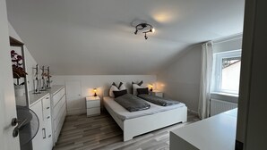 Un dormitorio con cama, mesitas de noche, cómoda y ventana.