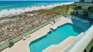 Une piscine avec vue sur une plage et un bâtiment doté d’un balcon.