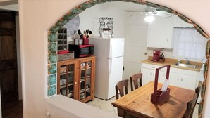 A kitchen with a refrigerator, microwave, and coffee maker. There is a wooden cabinet with dishes and a small table with chairs. - AZ Ranch House, near UofA & Banner Hosp /midtown (Tucson)