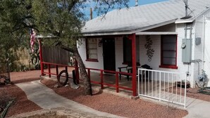 A building with a covered porch, a fenced area with a tree, and outdoor electrical equipment. - AZ Ranch House, near UofA & Banner Hosp /midtown (Tucson)
