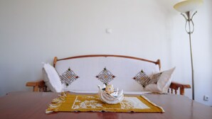Un letto rifatto con cura, con copripiumino e cuscini a fantasia, una testiera in legno e una lampada da comodino.