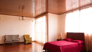 Un'ampia stanza con un letto grande, due poltrone e una ventola a soffitto.
