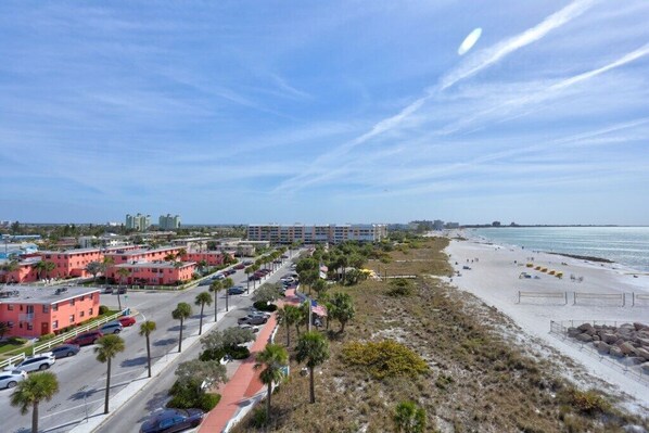 A coastal area with a beach, parking lots, and buildings.