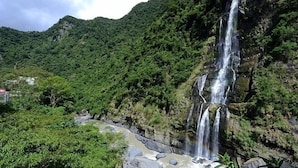 A waterfall cascading down a rocky cliff surrounded by lush greenery. - Wulai Shui An Hot Spring House (New Taipei City)