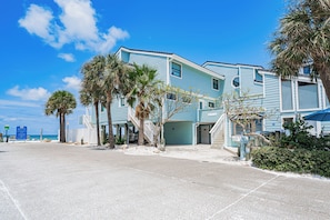 A beachfront property with a two-story building, a covered parking area, and a view of the ocean. - 1 Step to the Beach! Beachfront Condo with 3 Sunset Decks, Sleeps 6 (Indian Rocks Beach)