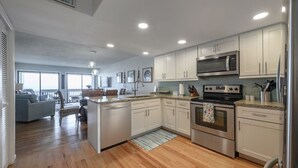 A modern kitchen with white cabinets, stainless steel appliances, and a central island. - 1 step and you are on the BEACH! Watch amazing sunsets from 3 decks! PremierHost (Indian Rocks Beach)