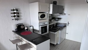 Une cuisine compacte équipée d’un four à micro-ondes, d’un four et d’un évier. On y trouve deux tabourets de bar et un tapis rouge sur le comptoir.