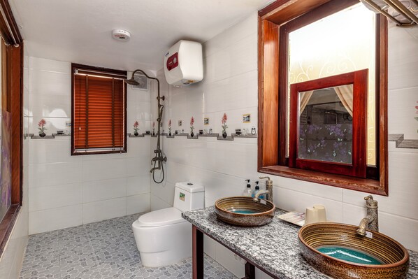 Une salle de bain comprenant des toilettes, un bidet et un lavabo agrémenté d’un receveur décoratif.