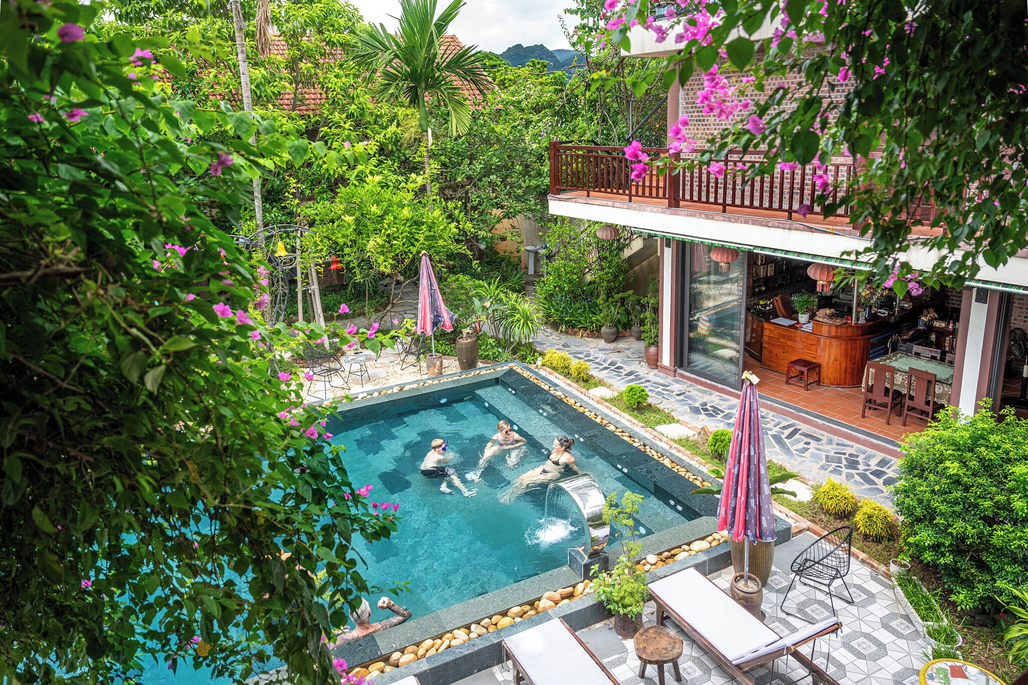 A swimming pool surrounded by lush greenery and a bar area with outdoor seating.