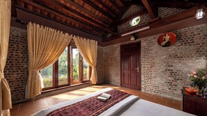 A room with a large bed, wooden beams, a brick wall, and a window with curtains. - Tamcoc Ngoc Linh Homestay (Nam Hoa Lu)
