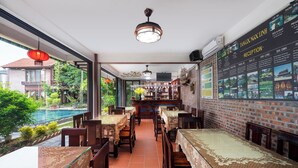 A restaurant with a pool view, brick walls, and a menu board. - Tamcoc Ngoc Linh Homestay (Nam Hoa Lu)