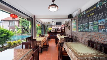 A restaurant with a pool view, brick walls, and a menu board.