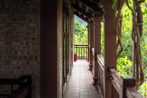 A covered outdoor corridor with a tiled floor, a red fire extinguisher, and a view of greenery. - Tamcoc Ngoc Linh Homestay (Nam Hoa Lu)