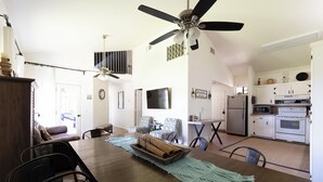 Ein geräumiger Wohnbereich mit Esstisch, Stühlen, einer Couch und einem Deckenventilator.