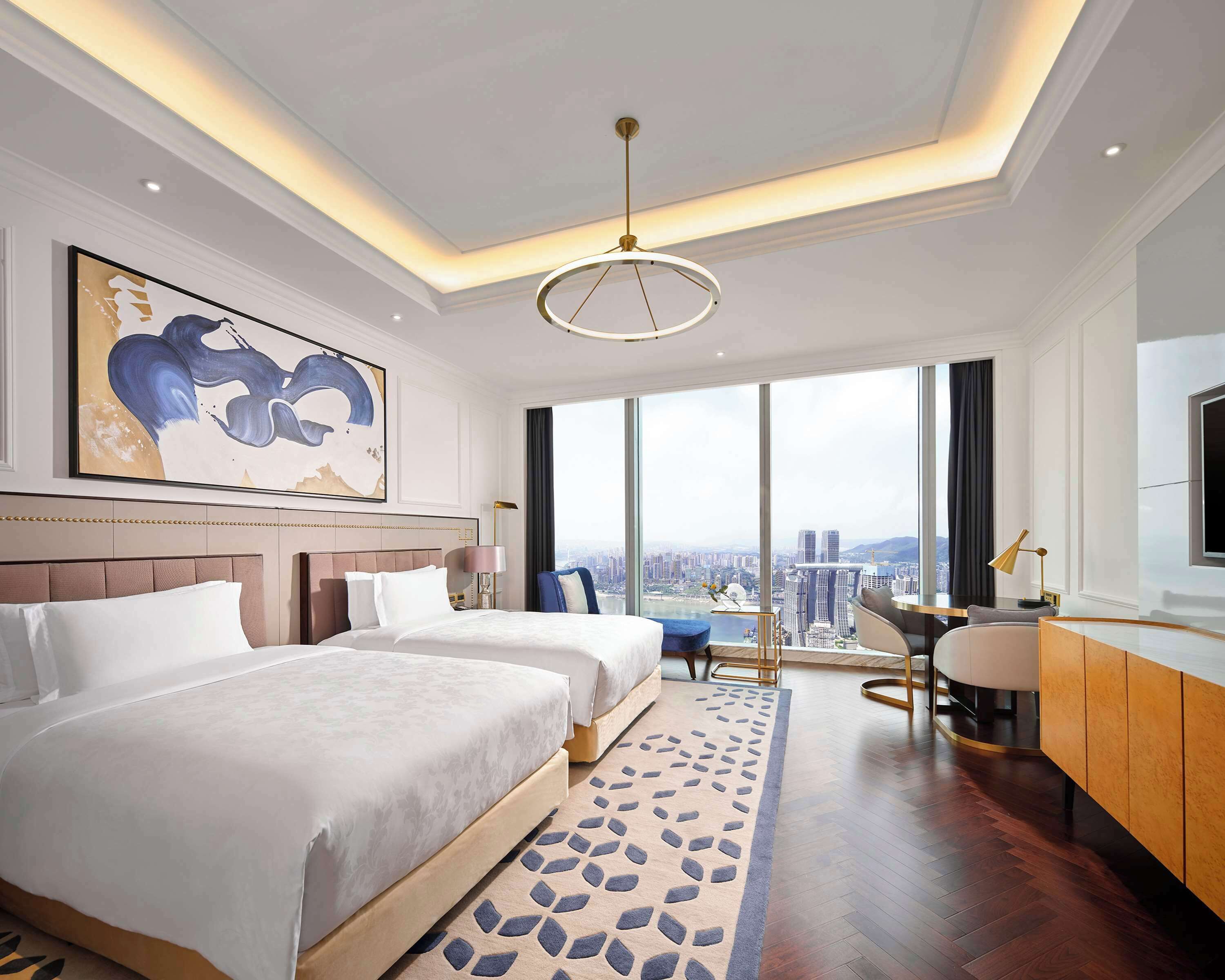 Habitación de hotel con una cama grande, un escritorio, una silla y vistas a la ciudad.