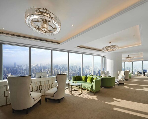 A spacious lounge with large windows offering a city view, elegant chandeliers, and modern seating arrangements. - The Lixury Hotel -The Unbound Collection by Hyatt (Chongqing)