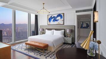 Una habitación de hotel moderna con una cama grande, vistas de la ciudad y una mesa redonda con un florero.