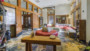 Eine großzügige Lobby mit einem Holzbuchtipp, einer roten Lounge und einer Schuhkollektion auf der rechten Seite.