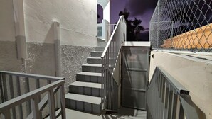 Una escalera con barandillas de metal que conduce a una entrada con portón.