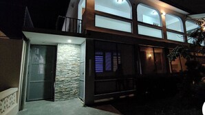 Una casa moderna de dos pisos con fachada de piedra, ventanas grandes y un balcón.