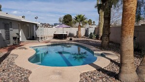 Un jardin avec une piscine, des palmiers et un espace patio.