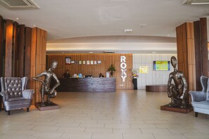 A reception area with a wooden reception desk, two bronze sculptures, and a reception desk with a sign that reads "ROYAL".