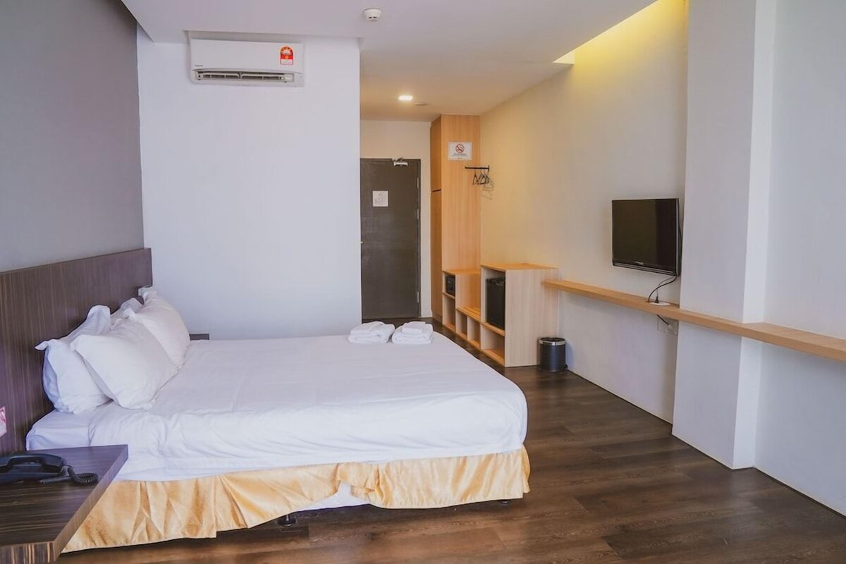 A hotel room with a bed, a TV, a desk, and a wardrobe.