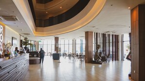 Eine geräumige Lobby mit gewölbter Decke, einem Empfangsbereich und einer Sitzecke mit Tischen und Stühlen.
