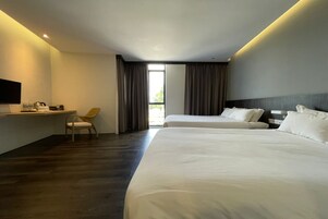 Quarto de hotel com duas camas, uma escrivaninha, uma cadeira e uma televisão.