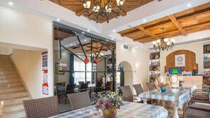 Un restaurant avec des nappes à carreaux, des chaises en osier et un lustre.