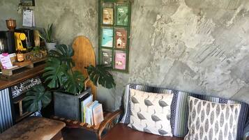 Um espaço de estar acolhedor com um banco de madeira, um banco estofado com almofadas estampadas e uma pequena mesa com livros e uma planta.