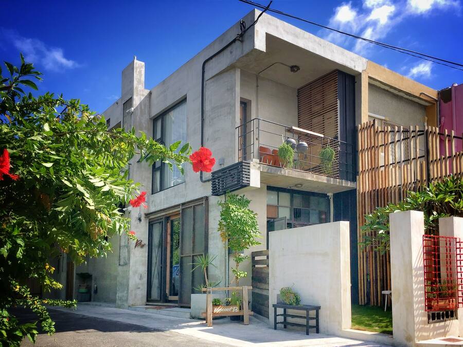 Un bâtiment moderne à deux étages, doté d’un balcon, de grandes fenêtres et de plantes en pot.