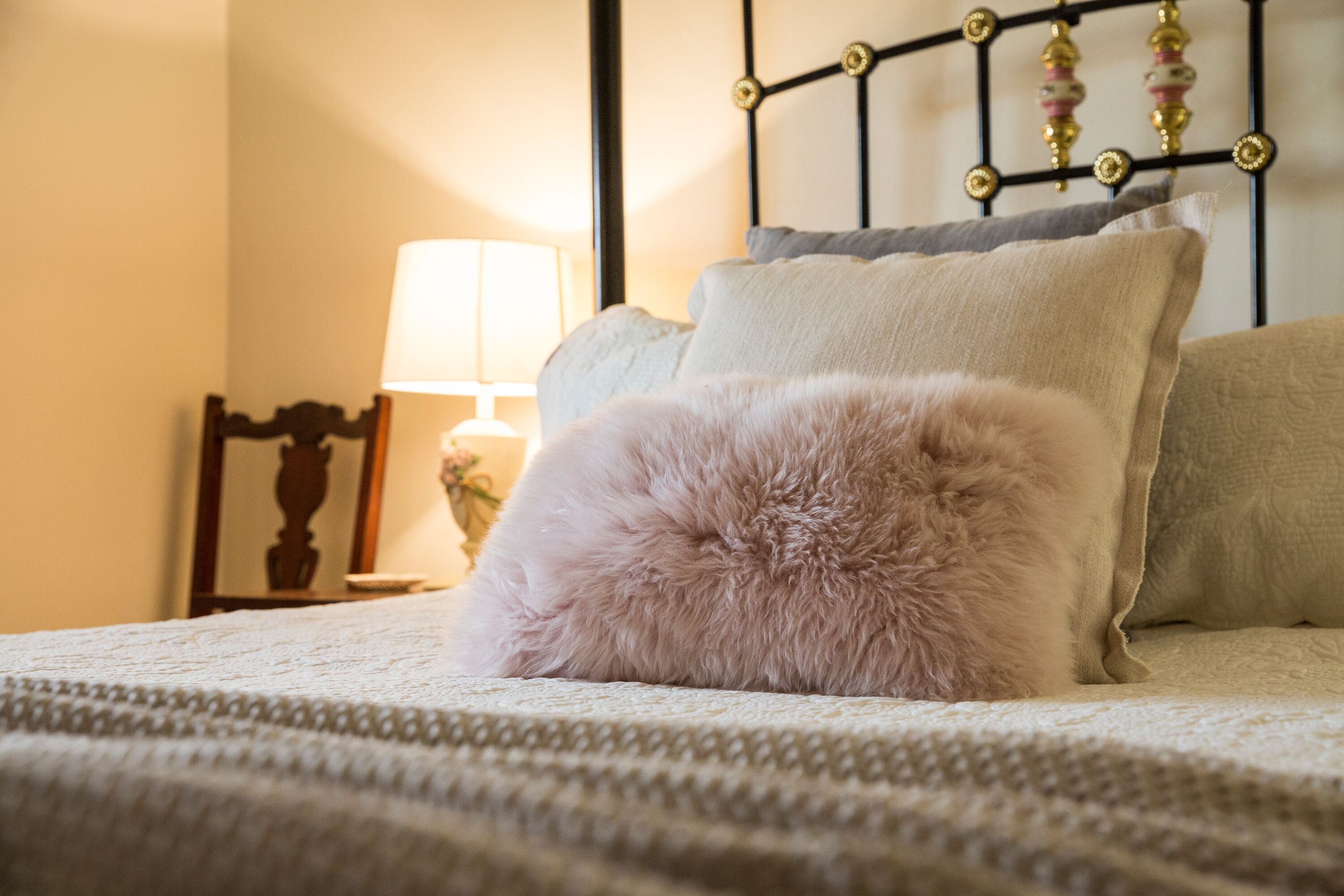 A bed with a fluffy pillow and a lamp on a bedside table.