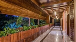 A corridor with wooden beams and a wooden fence with plants. - Floral Hotel · River Rhythms Pavilion Jinghong (Xishuangbanna Dai)