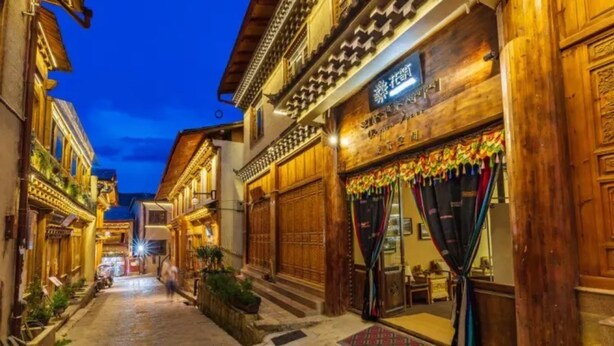Une rue étroite bordée de bâtiments traditionnels en bois, dont certains sont dotés de balcons et d’éléments décoratifs.