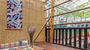 Une pièce au décor traditionnel, avec un mur en bambou, une table en bois ornée d’un vase et un tapis aux couleurs vives.