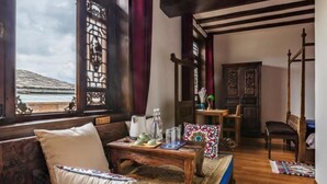 A traditional room with a wooden sofa, a table with a teapot, and a view of the sea through a window.