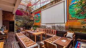 A traditional interior with wooden furniture, patterned rugs, and vibrant wall art.