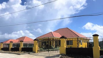 Un bâtiment jaune avec un toit rouge et une entrée fermée par un portail.