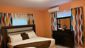 Een slaapkamer met een bed, een dressoir en een airconditioning.