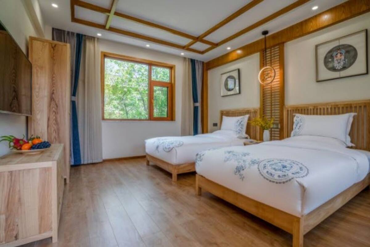 Une pièce avec deux lits en bois, une armoire en bois et une fenêtre avec des rideaux.