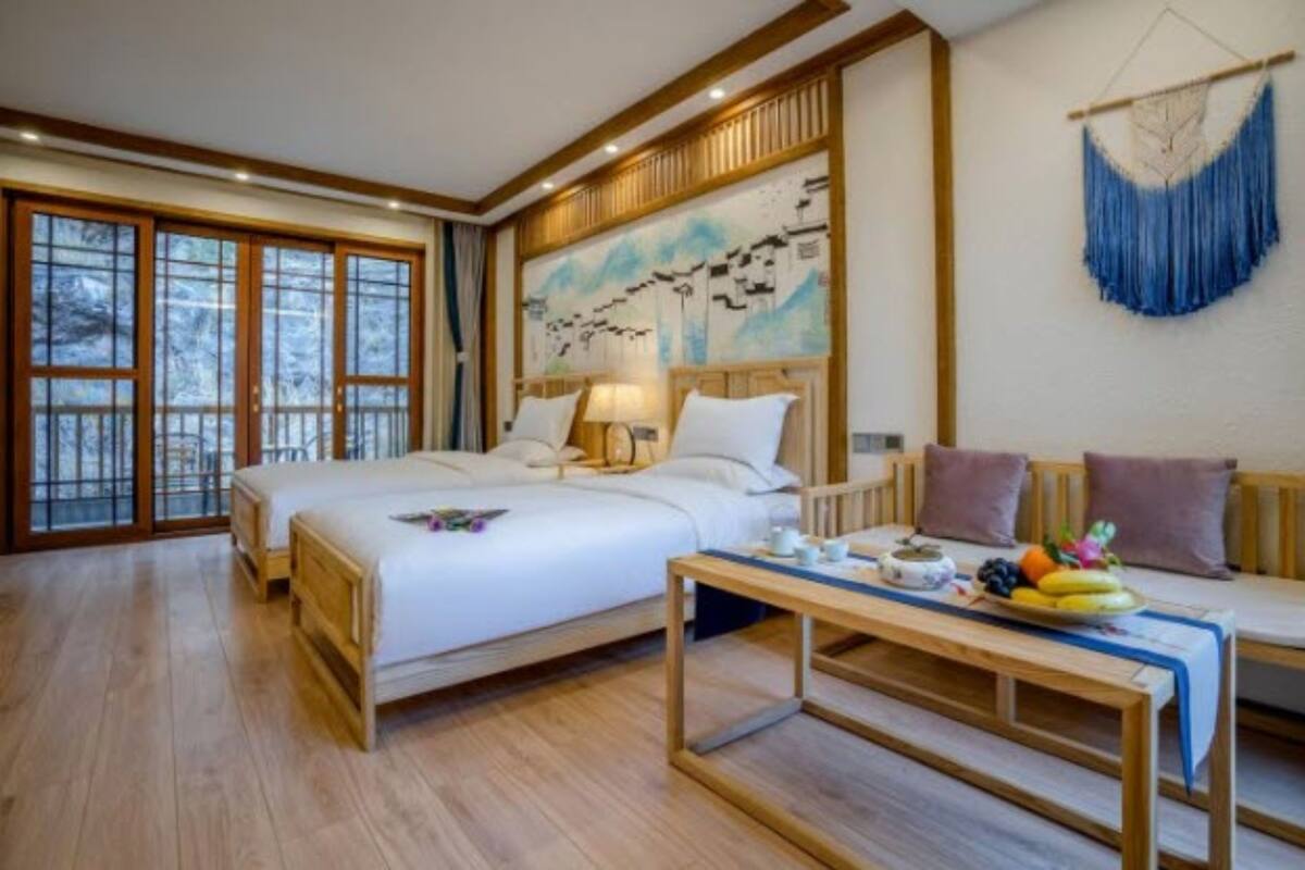 Une chambre d’hôtel avec un grand lit, un canapé, une table à manger avec des fruits et un tableau au mur.