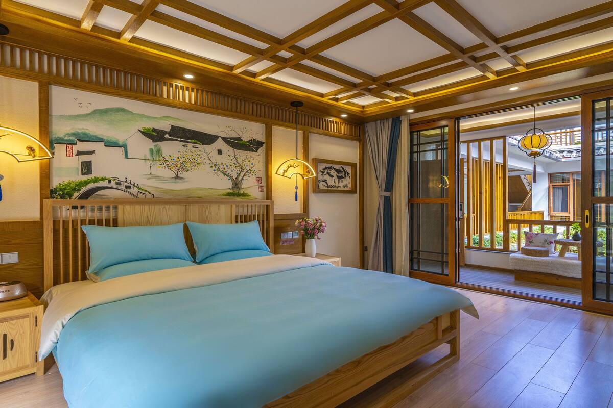 Une chambre à coucher avec un lit en bois, une table de chevet, une lampe fixée au mur et un tableau.