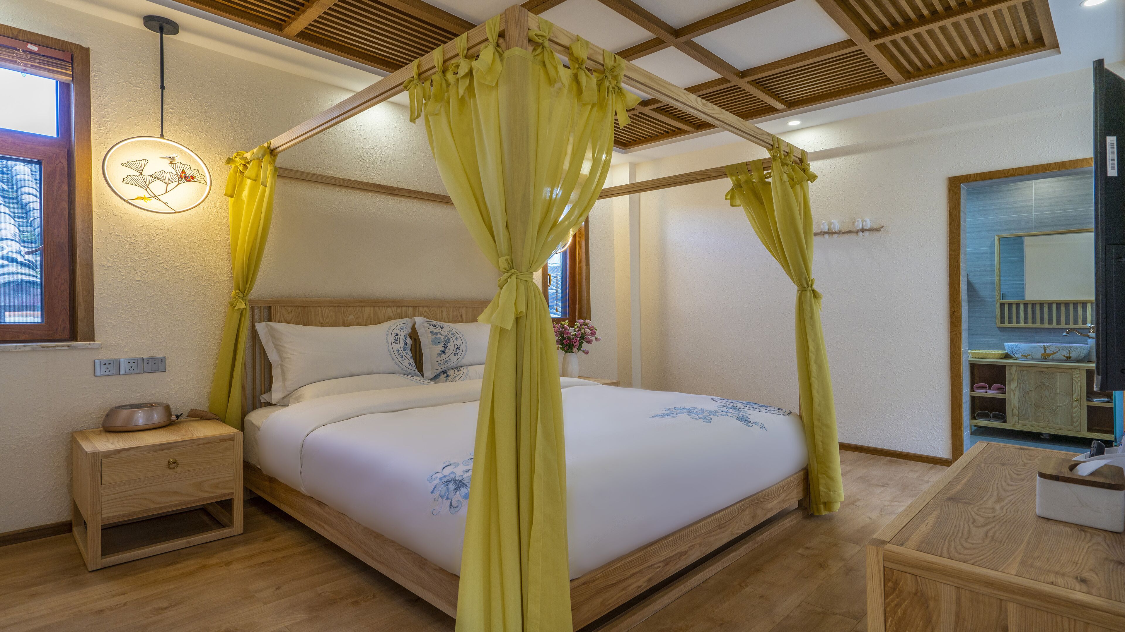 A bedroom with a four-poster bed, wooden headboard, bedside tables, a nightstand, a bedside lamp, a mirror, and a wooden dresser.