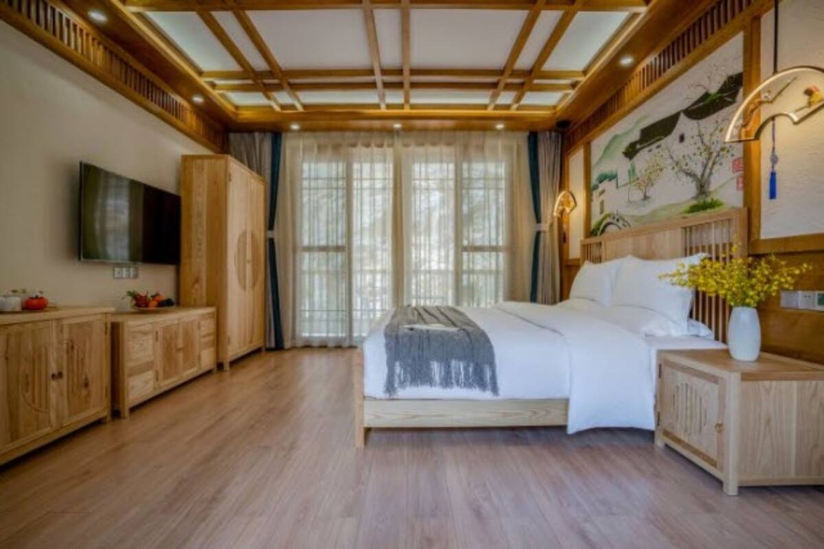 Une chambre avec un lit en bois, une télévision et un tableau accroché au mur.