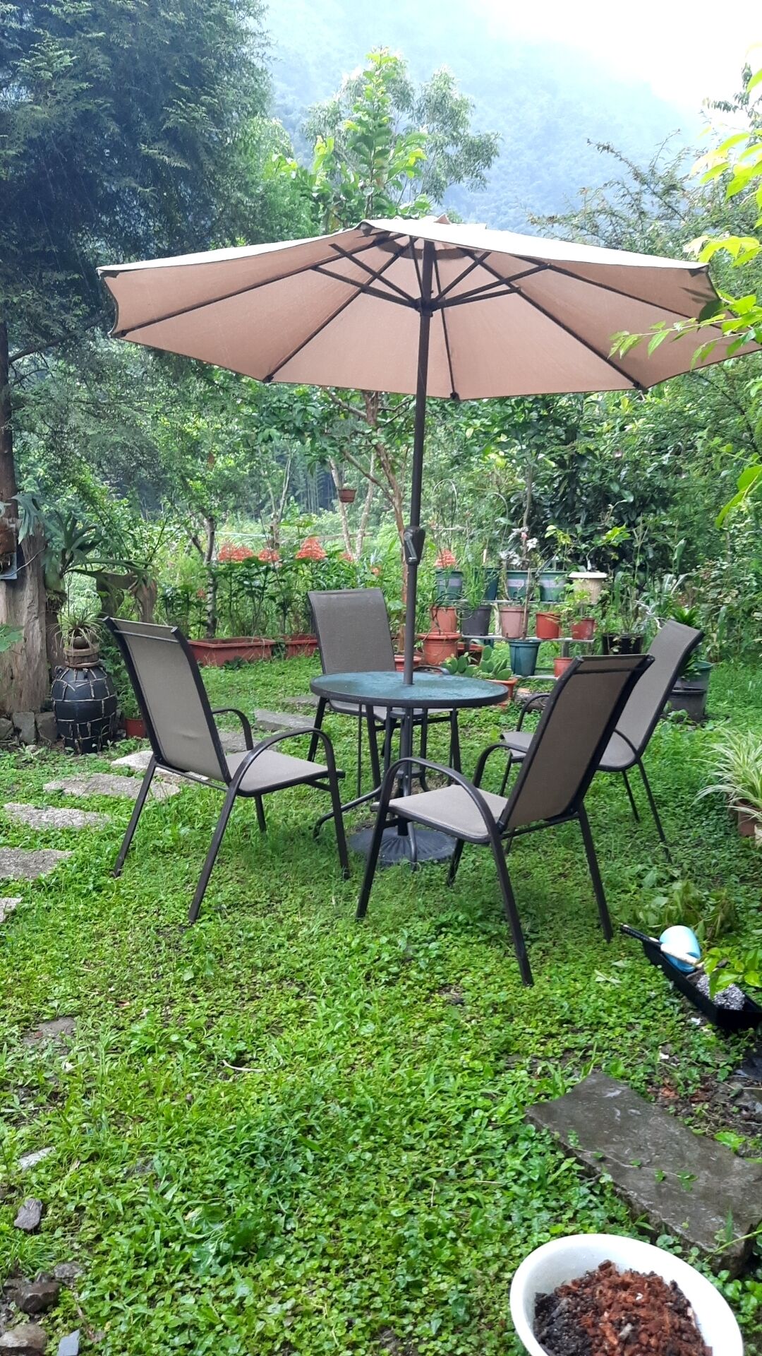 An outdoor patio with a round table, four chairs, and a large umbrella.