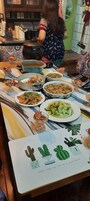 A dining table with various dishes, a teapot, and a decorative plate with cacti illustrations.
