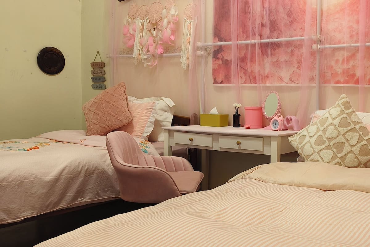 A bedroom with two beds, a vanity with a mirror, and a dresser.