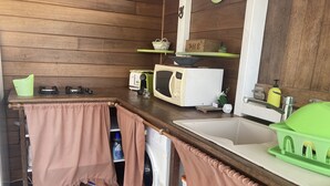 Een kleine keuken met houten wanden, een spoelbak, een magnetron, een gasfornuis en een wasmachine.