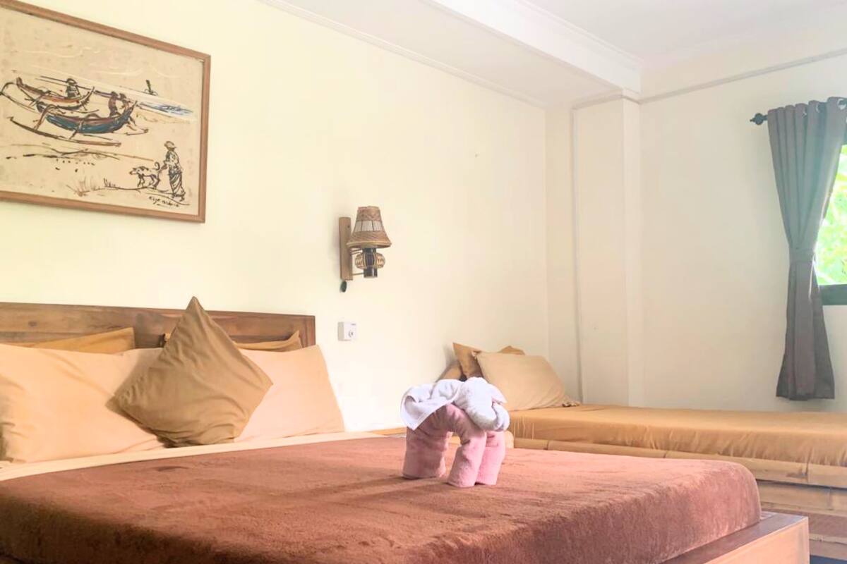 A room with a large bed, a smaller bed, a wall-mounted lamp, and a painting.